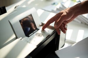 unikalne-drukarki-niefiskalne-zalety-jpg Ręka naciskająca przycisk na nowoczesnym urządzeniu, pokazuje drukarki niefiskalne zalety w łatwości obsługi.