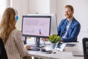 sprzedazowe-oprogramowanie-pos-jpg Dwóch pracowników biurowych korzysta z oprogramowania sprzedażowego POS na komputerach.