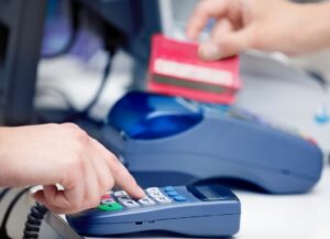 kasa-kasoterminal-pos-jpg Osoba używa kasoterminala POS do przeprowadzenia transakcji kartą.